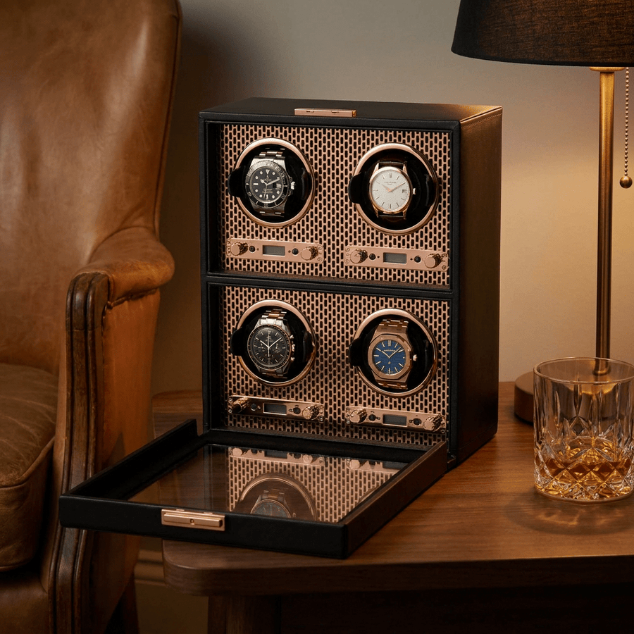 Wolf 1834 Axis watch winder voor 4 horloges in koperen (copper) afwerking, gevuld met verschillende luxe horloges, op een bijzettafel naast een leren fauteuil
