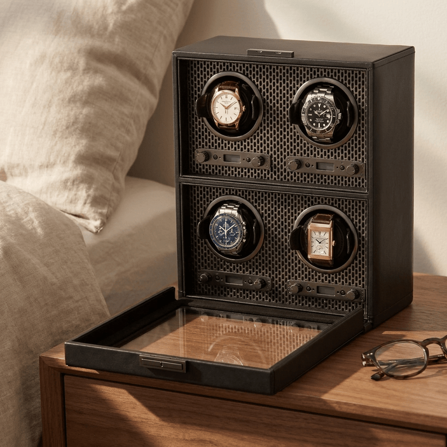 Wolf 1834 Axis watch winder voor 4 horloges in powder coat (mat zwart) afwerking, gevuld met verschillende luxe horloges, op een nachtkastje
