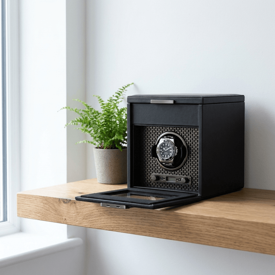 Wolf 1834 Axis watch winder met lade voor 1 horloge in powder coat (mat zwart) afwerking, gevuld met verschillende luxe horloges, op een eiken wandplank in een modern interieur
