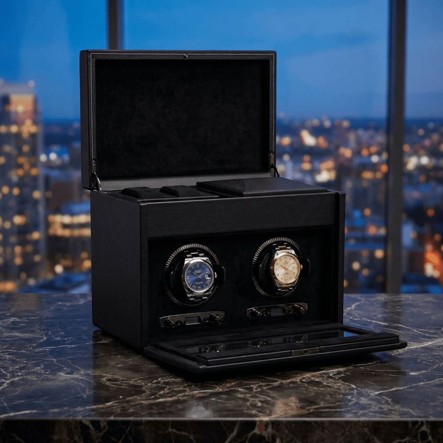 Wolf 1834 British Racing watch winder met lade voor 2 horloges in saphire black (zwart leer), gevuld met verschillende luxe horloges, op donker marmer met een avondlijke skyline op de achtergrond